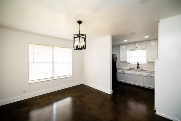 a view of a kitchen and an empty room with wooden floor and a window