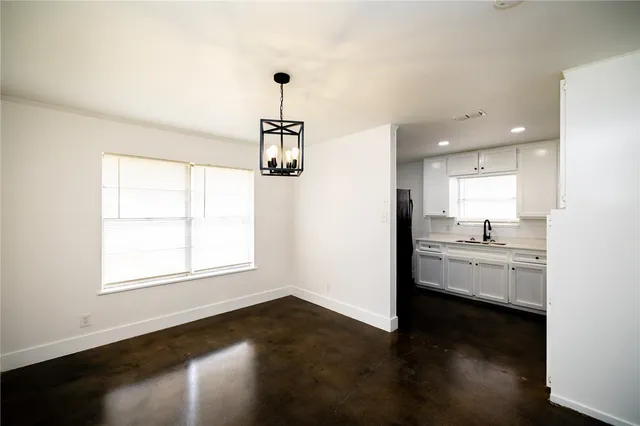 a view of a kitchen and an empty room with wooden floor and a window