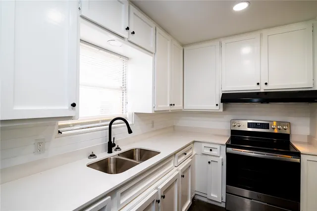 a kitchen with stainless steel appliances granite countertop white cabinets a sink and a stove