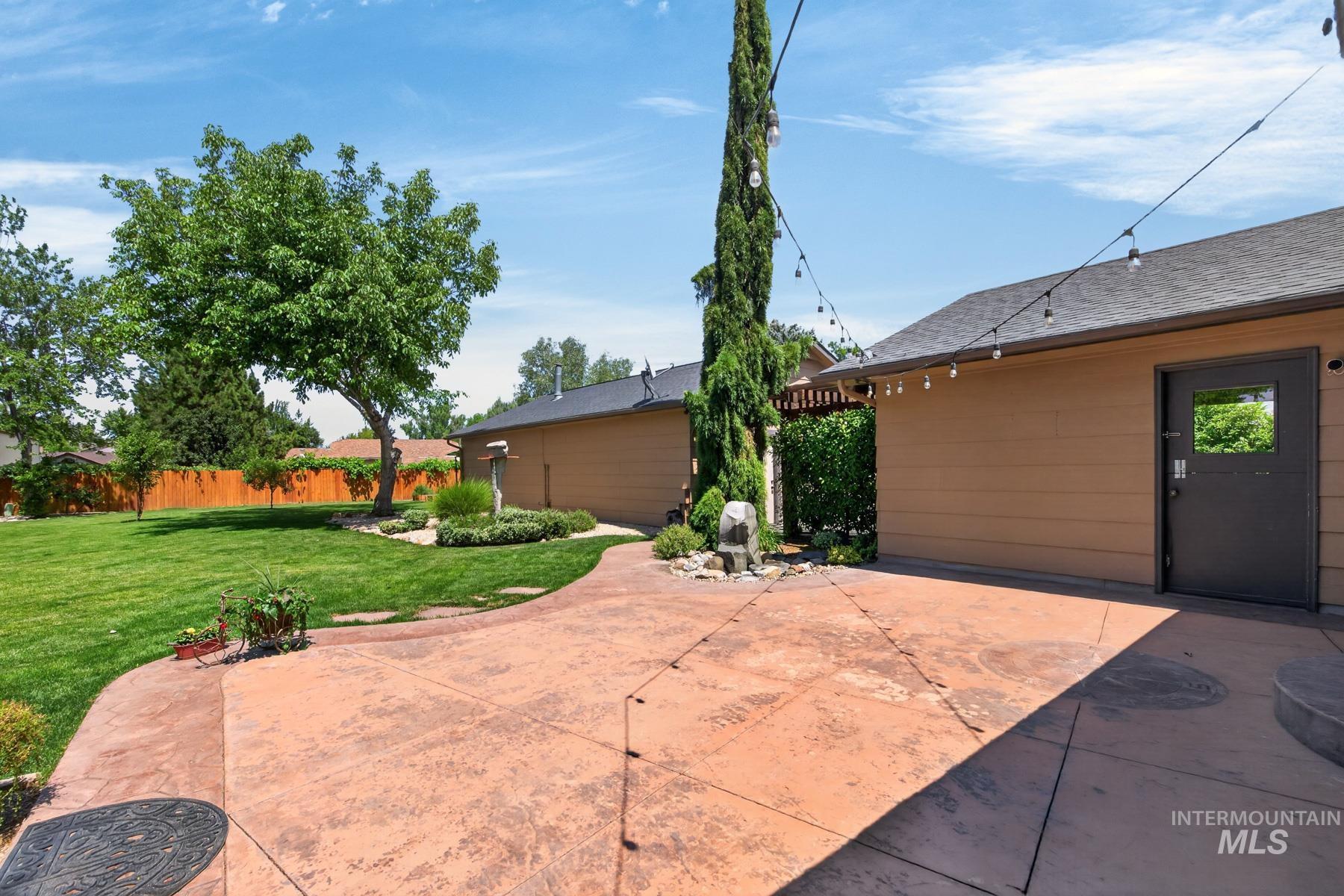 9622 Delaware Street Boise, ID 83709 - Photo 33 of 48 Expansive stamped concrete patio featuring string lighting, a manicured lawn, perimeter landscaping, and a privacy fence