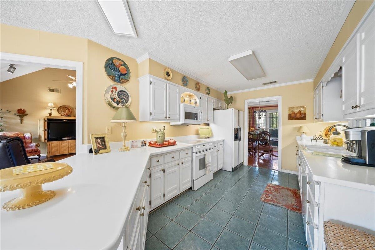 1880 Newfields Road Germantown, TN 38139 - Photo 17 of 34 Kitchen featuring dark tile patterned floors, light countertops, white cabinets, white appliances, and a textured ceiling