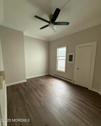 an empty room with wooden floor fan and windows