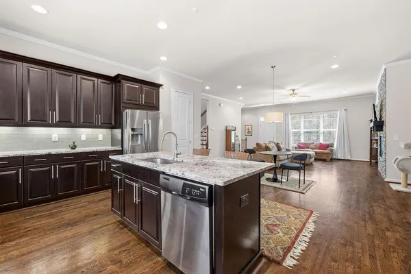 a kitchen with stainless steel appliances granite countertop a stove top oven a sink dishwasher and a dining table with wooden floor
