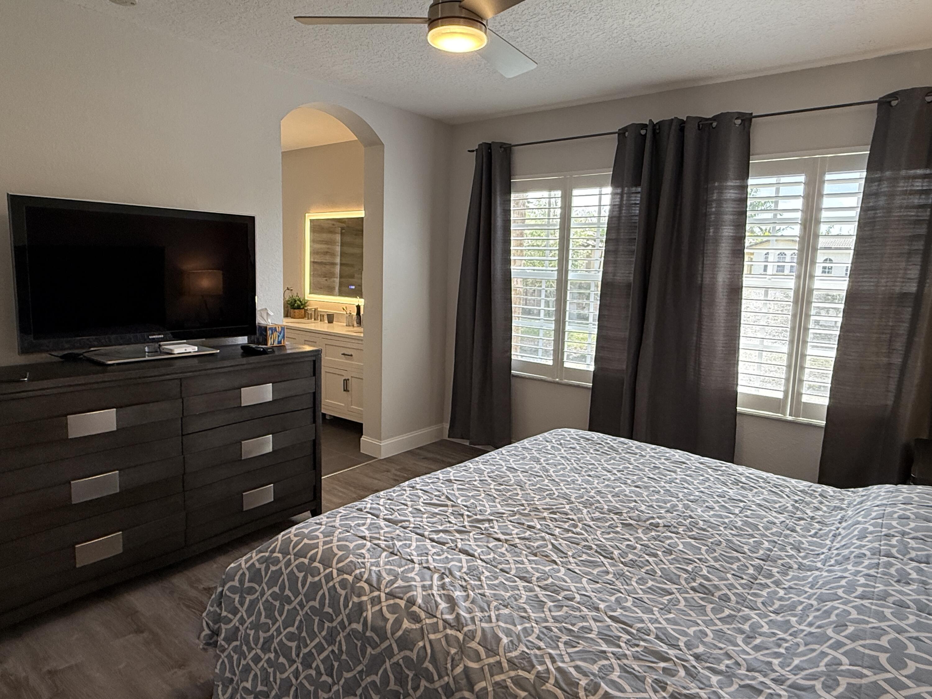 706 Duchess Court Palm Beach Gardens, FL 33410 - Photo 14 of 61 a bedroom with a bed and a flat screen tv