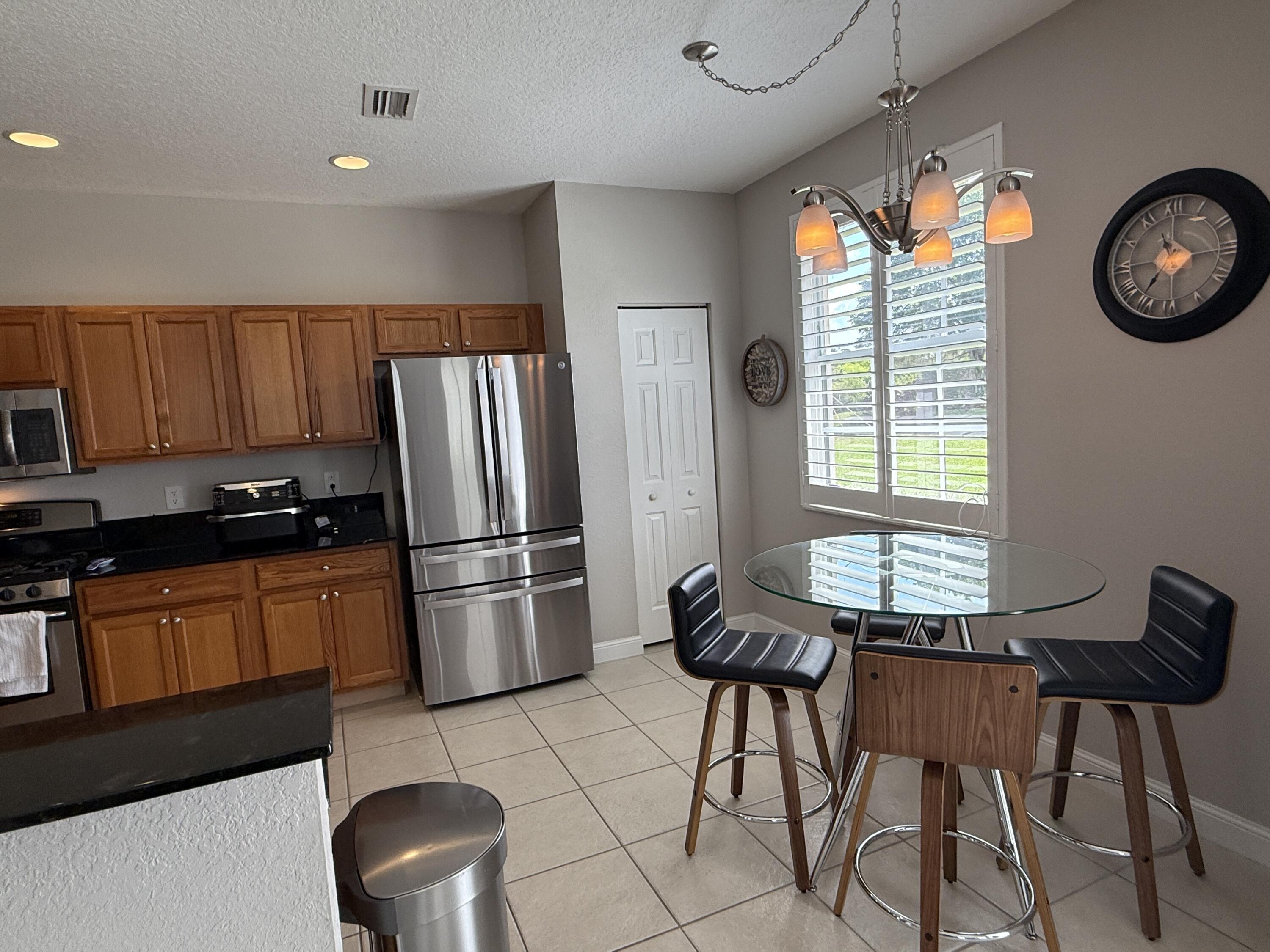 706 Duchess Court Palm Beach Gardens, FL 33410 - Photo 6 of 61 a kitchen with stainless steel appliances granite countertop a refrigerator a stove a sink a dining table and chairs