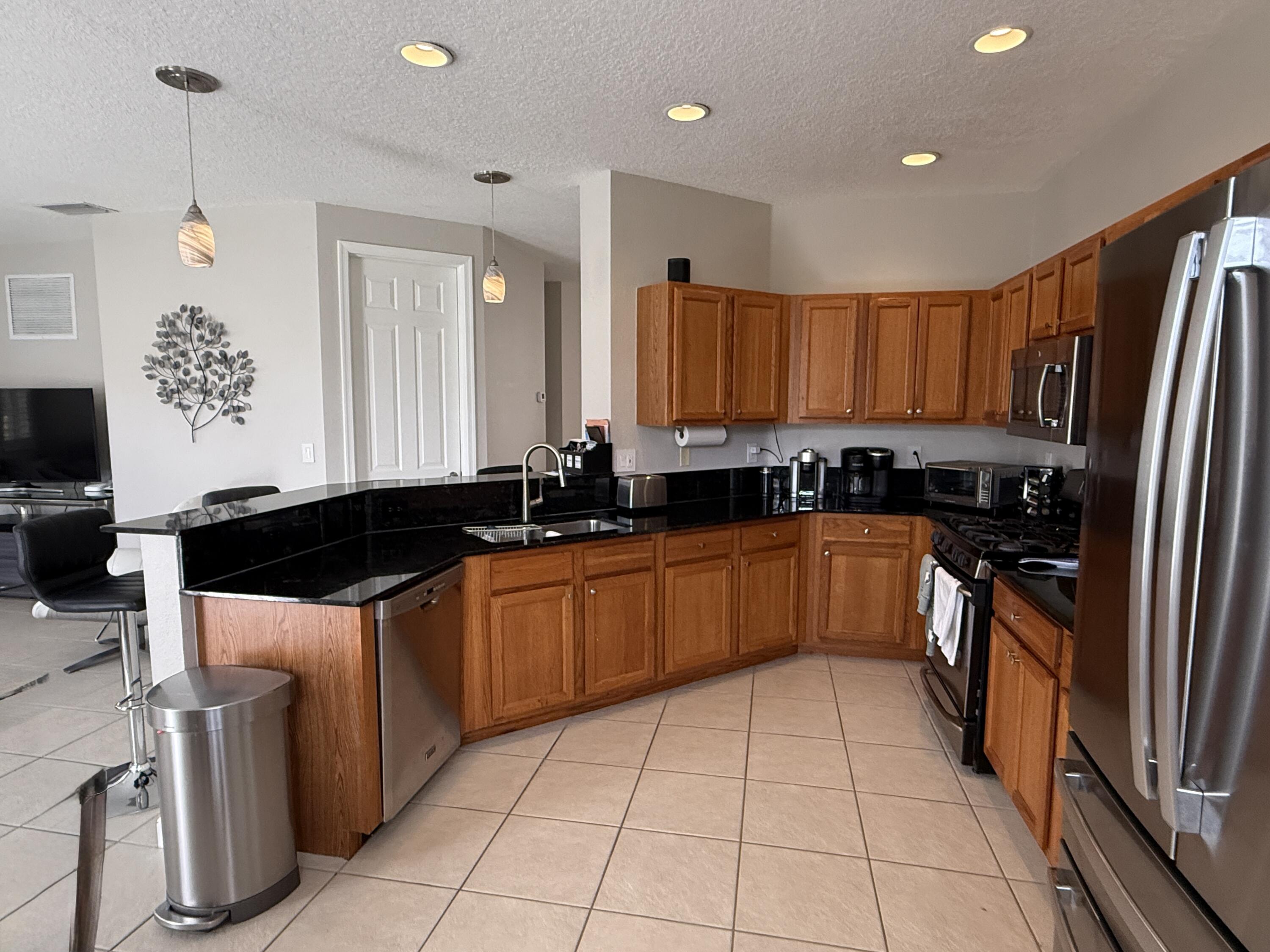 706 Duchess Court Palm Beach Gardens, FL 33410 - Photo 7 of 61 a large kitchen with stainless steel appliances a stove a sink and a refrigerator