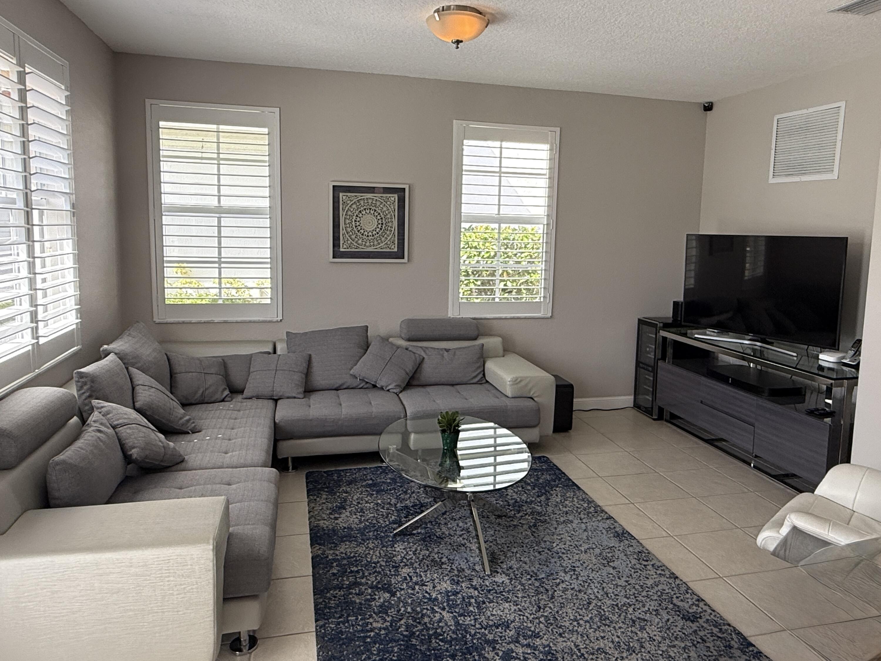 706 Duchess Court Palm Beach Gardens, FL 33410 - Photo 9 of 61 a living room with furniture a flat screen tv and a window