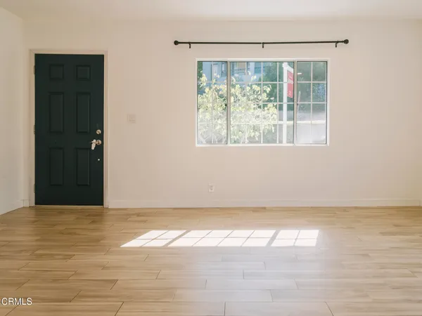 a view of an empty room with wooden floor and a window