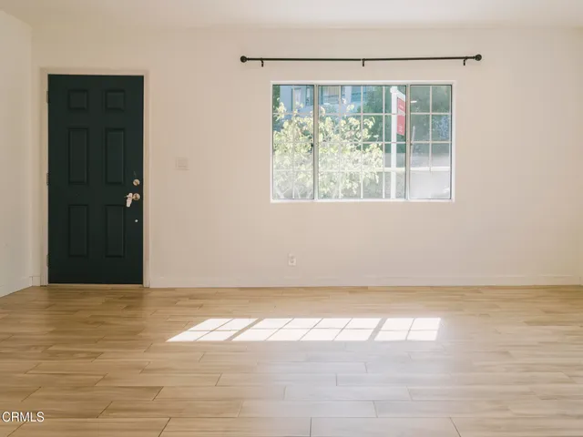 a view of an empty room with wooden floor and a window