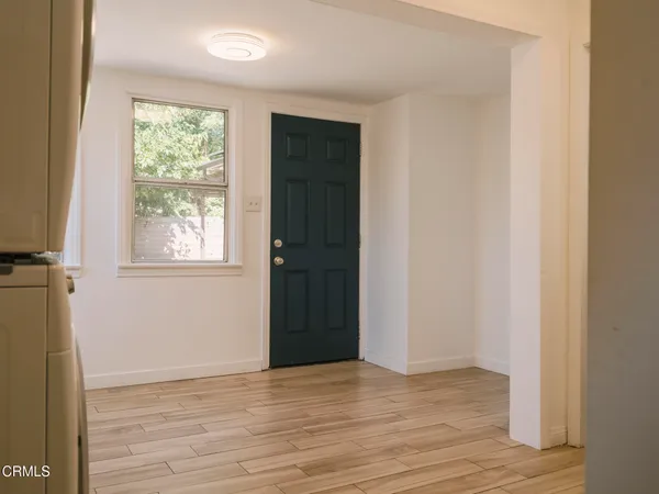 a view of an empty room with wooden floor and a window