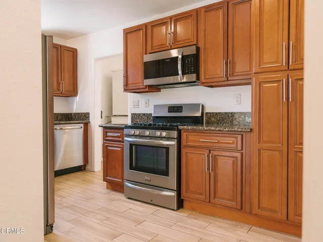 a kitchen with stainless steel appliances granite countertop a stove microwave and refrigerator
