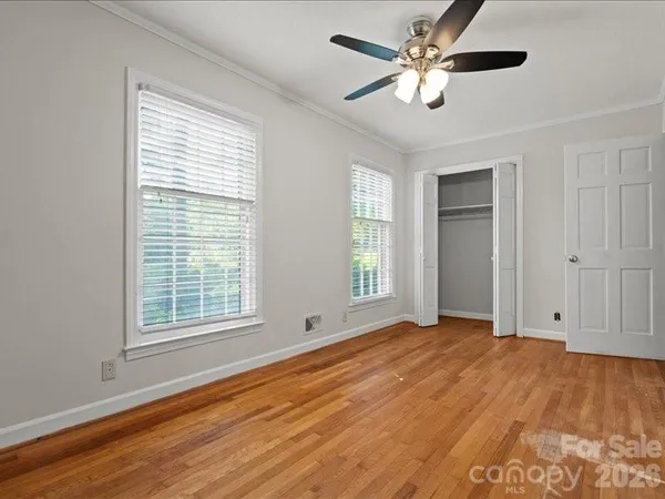 a view of empty room with wooden floor and fan