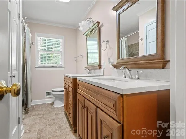 a bathroom with a granite countertop sink a toilet and a window