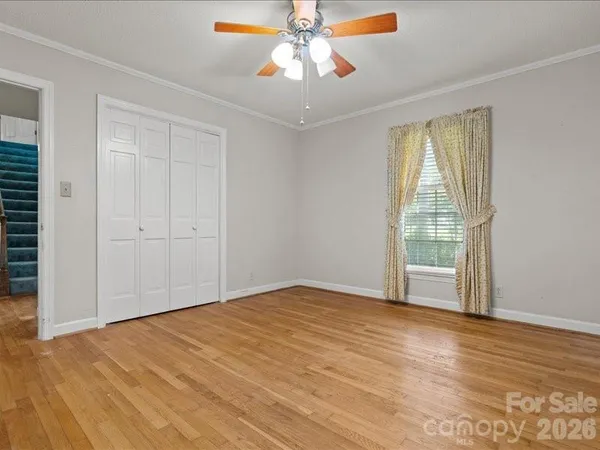 a view of empty room with wooden floor and fan