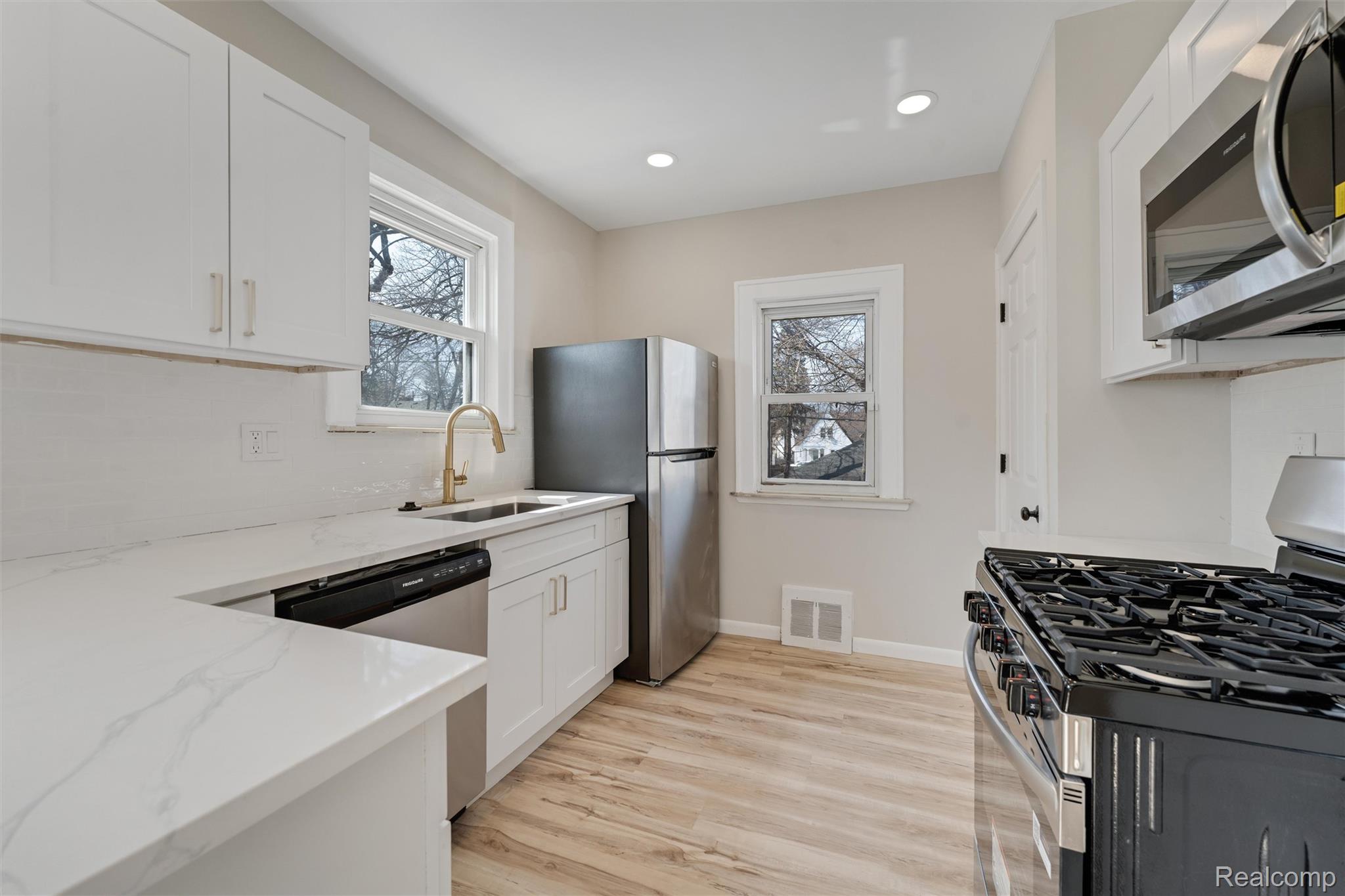 917 Perry Street Pontiac, MI 48340 - Photo 14 of 37 Kitchen with stainless steel appliances, white cabinetry, light wood-type flooring, light stone countertops, and recessed lighting