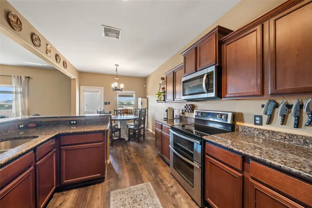 a kitchen with granite countertop wooden cabinets a stove top oven and granite counter tops
