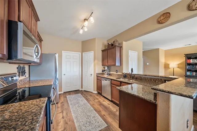 a large kitchen with stainless steel appliances granite countertop a sink stove and refrigerator