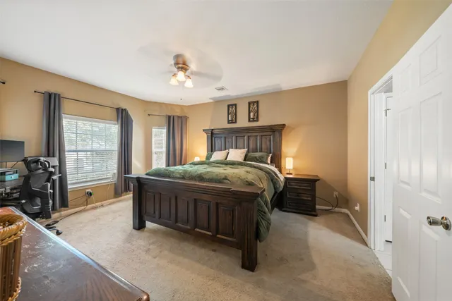 a bedroom with a large bed a chandelier and windows