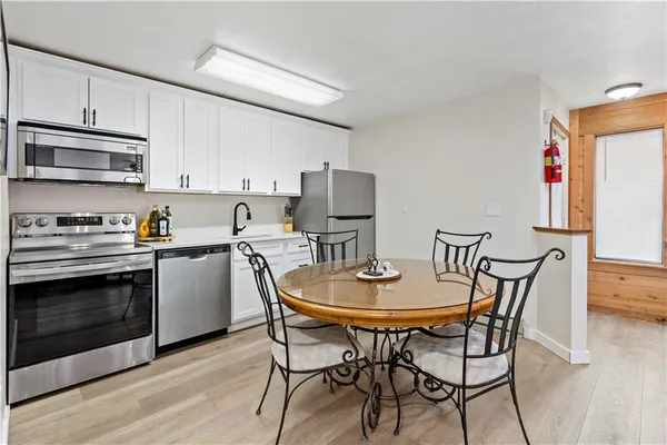 a kitchen with stainless steel appliances kitchen island granite countertop a dining table chairs and a refrigerator