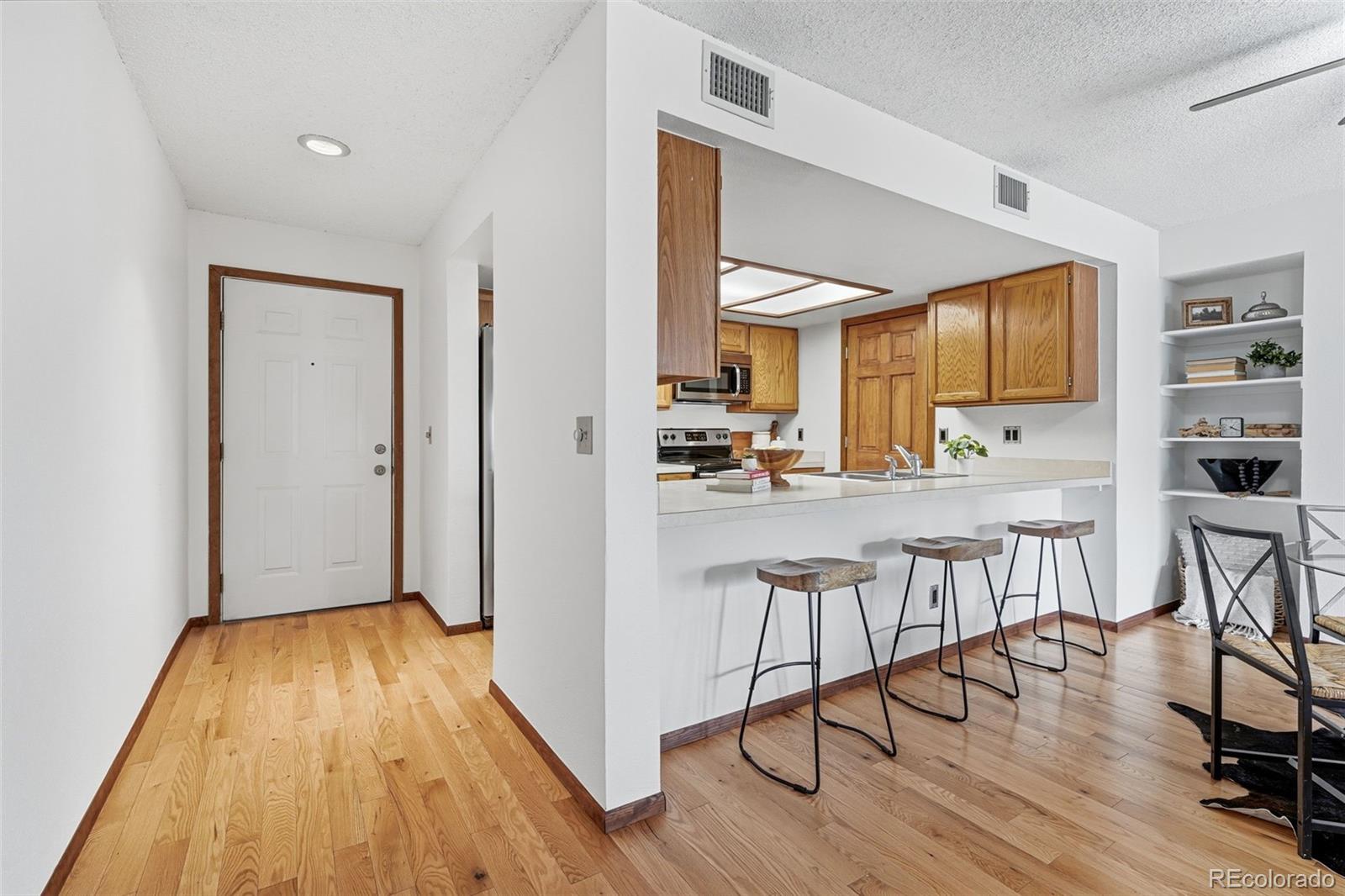 23557 Genesee Village Road, Unit A Golden, CO 80401 - Photo 6 of 38 a kitchen with stainless steel appliances granite countertop a stove top oven a sink and white cabinets with wooden floor next to windows