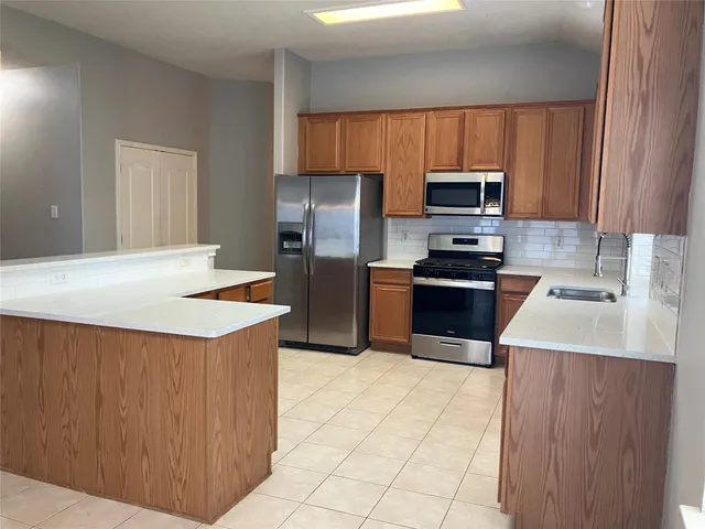 a kitchen with stainless steel appliances a stove a sink a microwave and a refrigerator