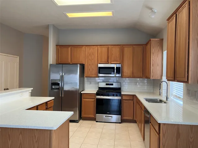 a kitchen with stainless steel appliances a sink a stove a microwave a sink a refrigerator and cabinets