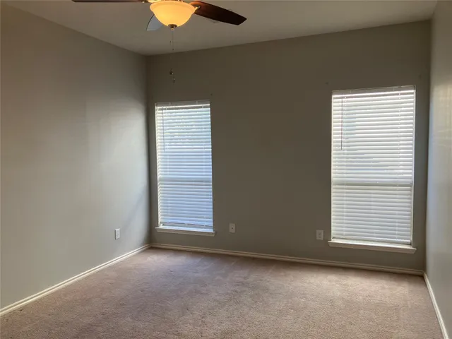 an empty room with a window and a chandelier fan