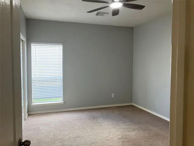 an empty room with a window and a ceiling fan