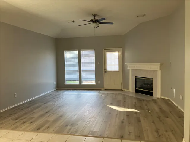 wooden floor fireplace and windows in an empty room