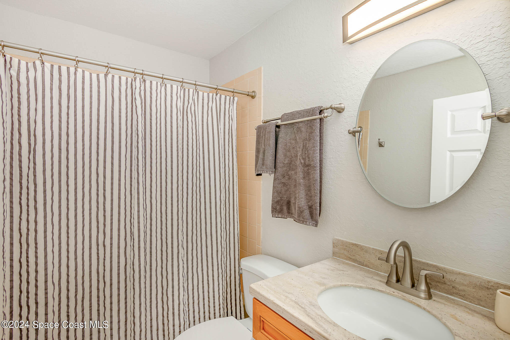 300 South Banana River Boulevard, Unit 305 Cocoa Beach, FL 32931 - Photo 23 of 36 a bathroom with a granite countertop sink a mirror a vanity and toilet