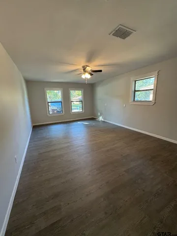 an empty room with windows and ceiling fan