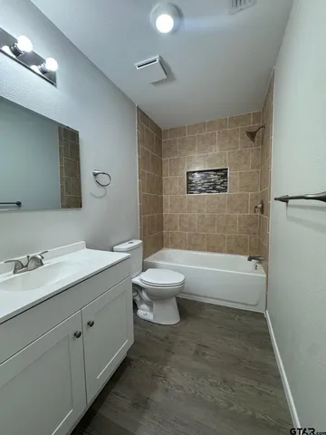 a bathroom with a granite countertop sink toilet a large mirror a bathtub and vanity