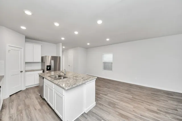a kitchen that has a lot of cabinets in it and wooden floor