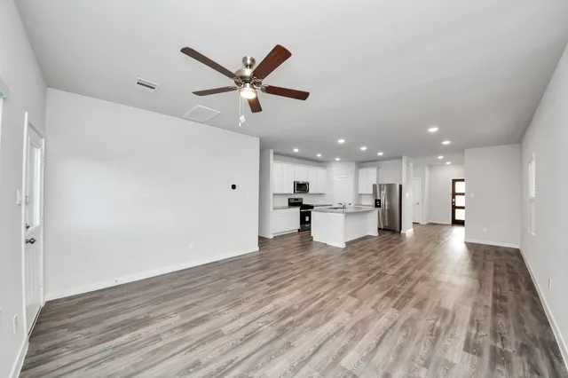 a view of an empty room with wooden floor and a window