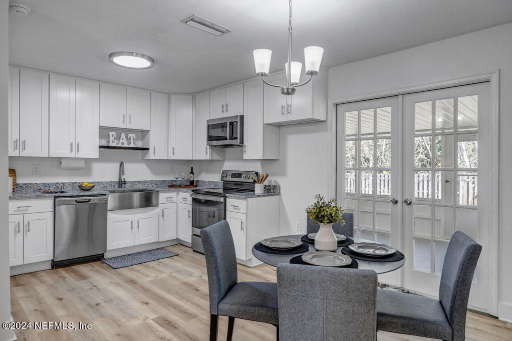 903 Royal Road St. Augustine, FL 32086 - Photo 14 of 32 a kitchen with stainless steel appliances granite countertop a stove top oven a sink dishwasher a dining table and chairs with wooden floor
