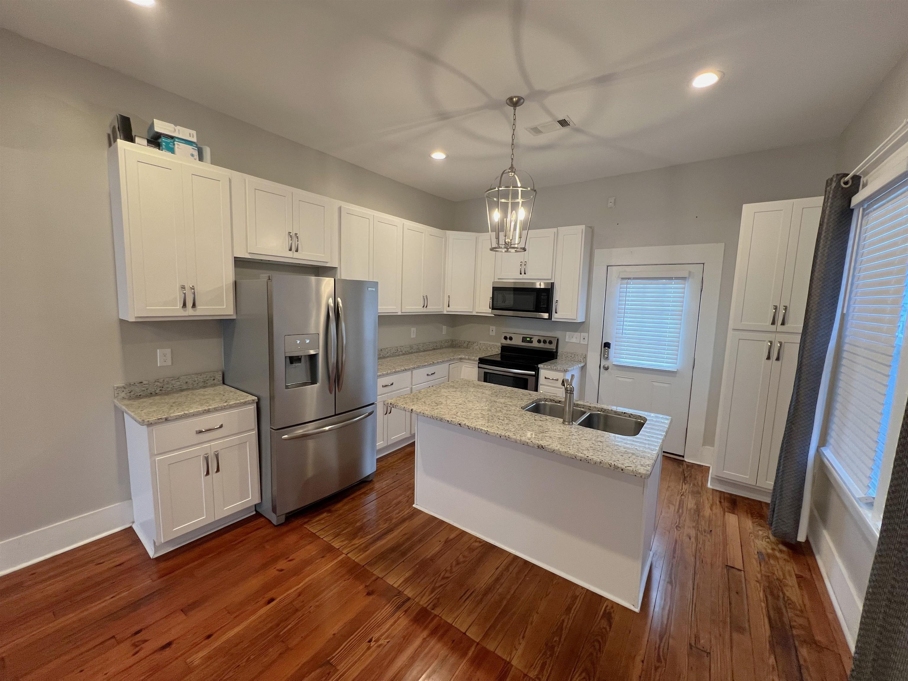 897 South Cox Street Memphis, TN 38104 - Photo 3 of 14 a kitchen with a refrigerator a sink dishwasher a stove and white cabinets with wooden floor
