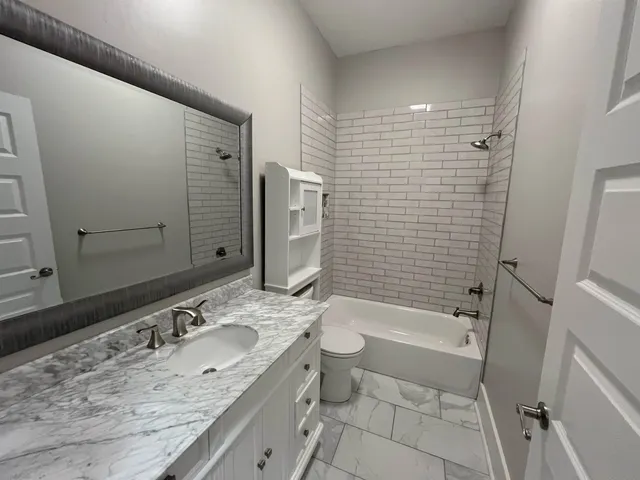 a bathroom with a granite countertop sink toilet and shower