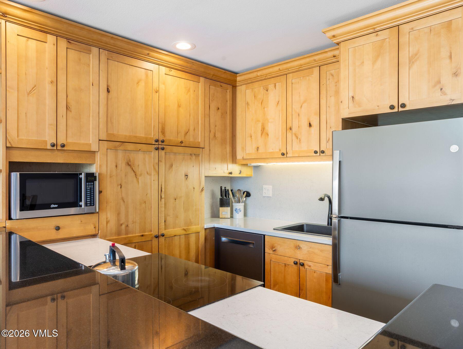 1100 North Frontage Road West, Unit 1503 Vail, CO 81657 - Photo 14 of 32 a kitchen with stainless steel appliances a refrigerator sink and cabinets