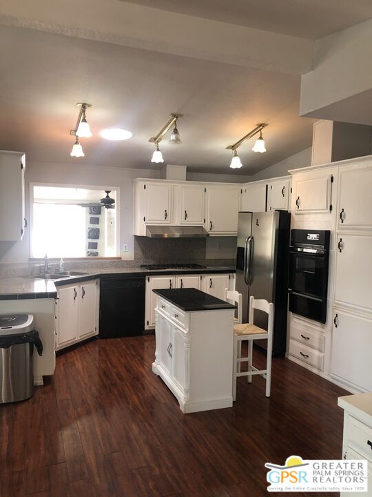 69525 Dillon Road, Unit 73 Desert Hot Springs, CA 92241 - Photo 12 of 48 a kitchen with stainless steel appliances kitchen island granite countertop a stove a refrigerator a sink a dining table and chairs with wooden floor