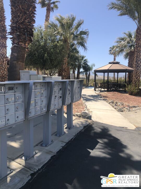 69525 Dillon Road, Unit 73 Desert Hot Springs, CA 92241 - Photo 37 of 48 a view of a patio with table and chairs under an umbrella with palm trees