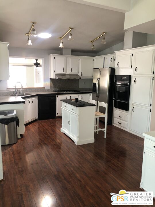 69525 Dillon Road, Unit 73 Desert Hot Springs, CA 92241 - Photo 43 of 48 a kitchen with stainless steel appliances kitchen island granite countertop a stove a refrigerator a sink a dining table and chairs with wooden floor