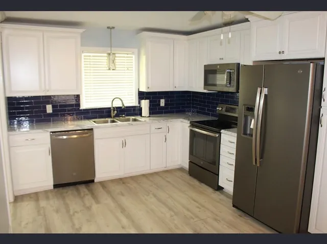a kitchen with a sink white cabinets and stainless steel appliances