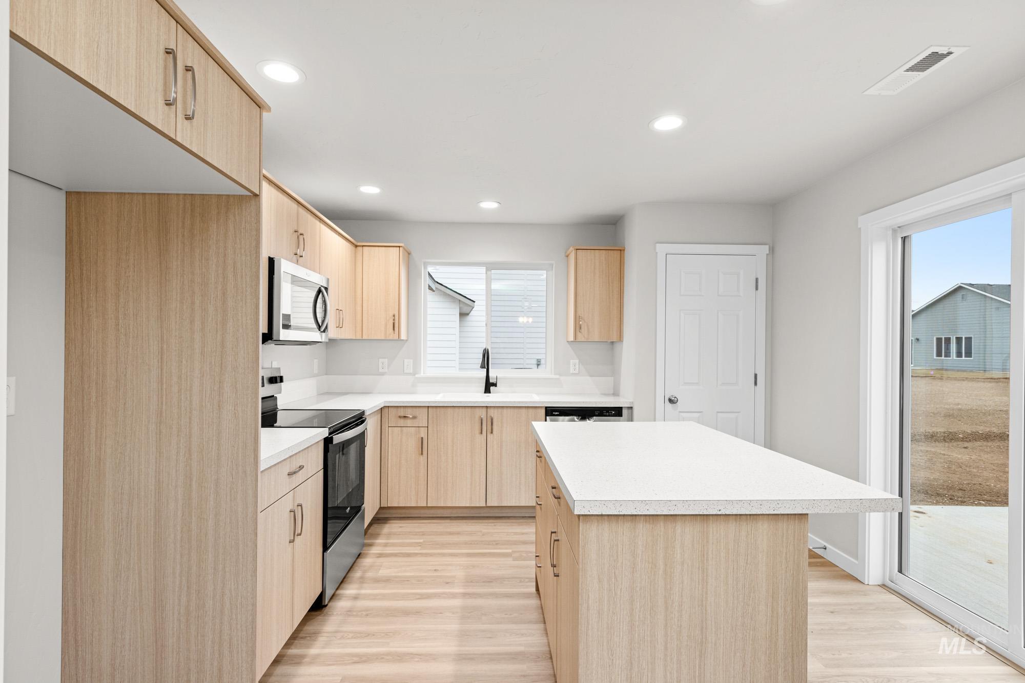 13711 Inman Court Caldwell, ID 83607 - Photo 4 of 16 Kitchen with light wood finish cabinetry, stainless steel appliances, light wood finished floors, a kitchen island, and recessed lighting