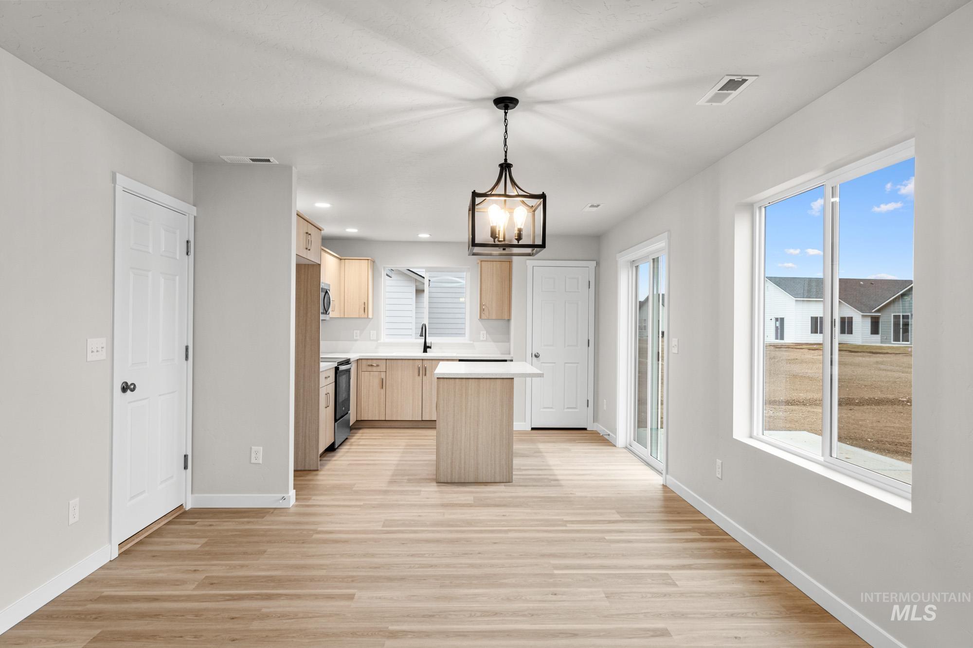 13711 Inman Court Caldwell, ID 83607 - Photo 6 of 16 Kitchen featuring light wood finish cabinetry, hanging lights, light countertops, a center island, and light wood-style floors