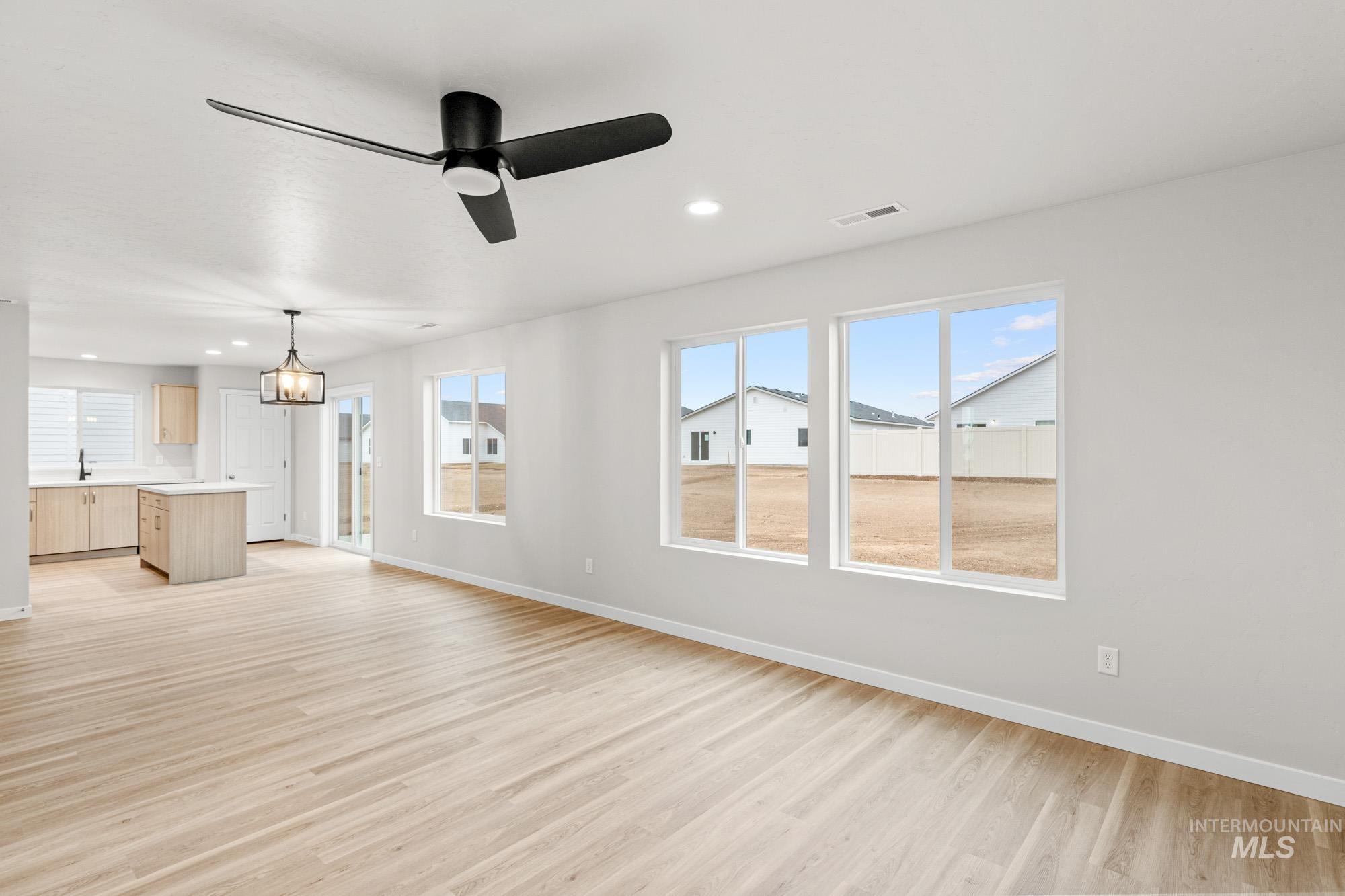13711 Inman Court Caldwell, ID 83607 - Photo 7 of 16 Unfurnished living room with light wood finished floors, a ceiling fan, and suspended lighting