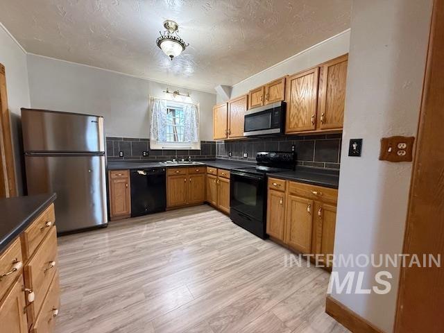 902 East Main Street Weiser, ID 83672 - Photo 12 of 45 Kitchen featuring dark countertops, black appliances, backsplash, wood finish cabinetry, and a textured ceiling