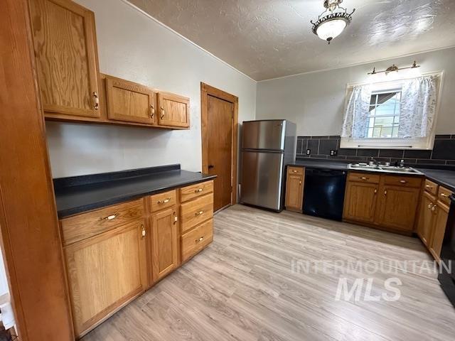 902 East Main Street Weiser, ID 83672 - Photo 13 of 45 Kitchen featuring dark countertops, freestanding refrigerator, black dishwasher, wood finish cabinetry, and a textured ceiling