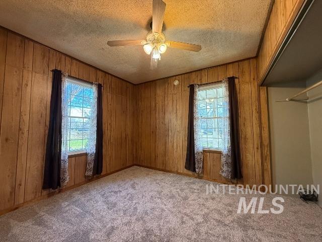 902 East Main Street Weiser, ID 83672 - Photo 17 of 45 Carpeted empty room with ceiling fan, wood walls, and a textured ceiling