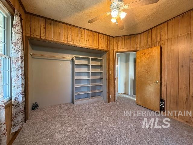 902 East Main Street Weiser, ID 83672 - Photo 27 of 45 Unfurnished bedroom featuring a textured ceiling, a ceiling fan, carpet floors, wooden walls, and a closet