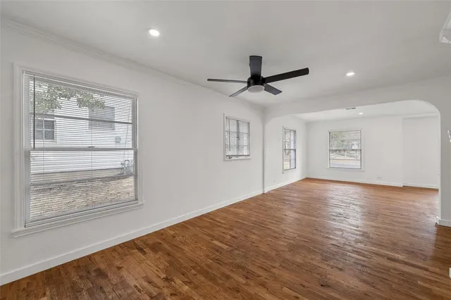a view of an empty room with a window and wooden floor
